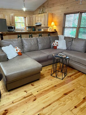 A modern living room with a sectional sofa, a small side table, and wooden flooring.