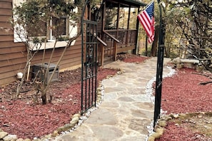 Un sendero de piedra que conduce a una terraza de madera con una bandera estadounidense.