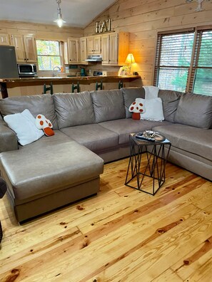 A modern living room with a sectional sofa, a small side table, and wooden flooring.