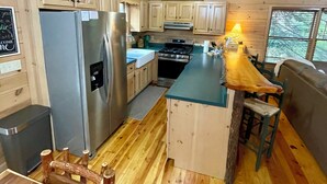 Una cucina con mobili in legno, un frigorifero in acciaio inossidabile, un piano cottura e un'isola in legno con sgabelli.
