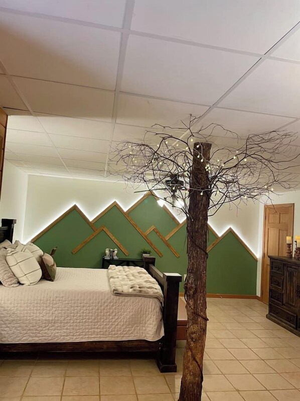 Un dormitorio con cama, cómoda y un árbol con luces.