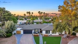 A modern two-story house with a garage, a well-maintained lawn, and a driveway leading to the entrance. - Spacious Modern Oasis with Pool, Hot Tub, and Putting in Scottsdale (Phoenix)