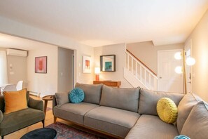 A living room with a sofa, a chair, a small table, and a staircase. - Sunroom Expansive Patio Fenced Yard! (Eastham)