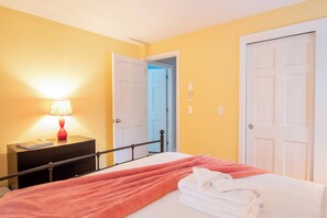 A bedroom with a bed, a nightstand with a lamp, and two doors.