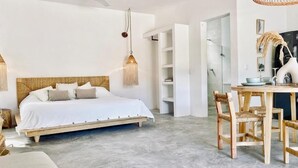A bedroom with a bed, bedside tables, a hanging light fixture, and a wooden chair. - Casa Macay (Tulum)
