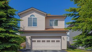 Ein zweistöckiges Haus mit Garage, umgeben von Bäumen.