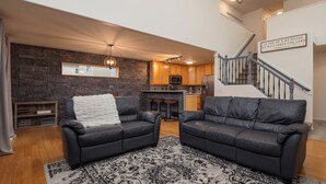 Ein modernes Wohnzimmer mit zwei Ledersofas, einem schwarz-weißen Teppich und einer Steinwand.
