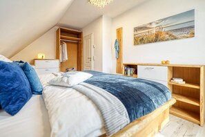 Quarto com cama, guarda-roupa, escrivaninha e estante de livros.