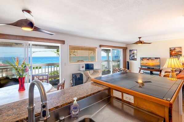 A modern kitchen with a large island, a built-in oven, and a view of the ocean. - Ocean View 2 Bedroom Kahalu'u Reef KR301 (Kailua Kona)