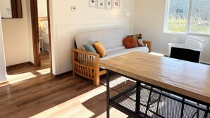 A cozy room with a wooden dining table, a cushioned sofa, a white radiator, and framed pictures on the wall. - Lovely apartment in the heart of Kenai (Kenai)