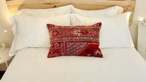 A bed with white linens, a wooden headboard, and a single red patterned pillow. - Lovely apartment in the heart of Kenai (Kenai)