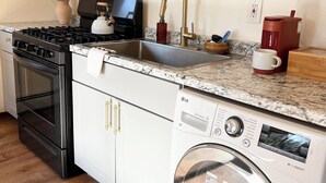 A kitchen with a stove, microwave, sink, and washing machine. - Lovely apartment in the heart of Kenai (Kenai)
