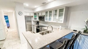 Uma cozinha moderna com armários brancos, eletrodomésticos de aço inoxidável e bancada de granito.