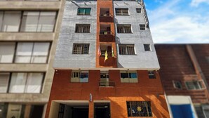Un edificio de varios pisos con fachadas de ladrillo y piedra, múltiples ventanas y balcones.