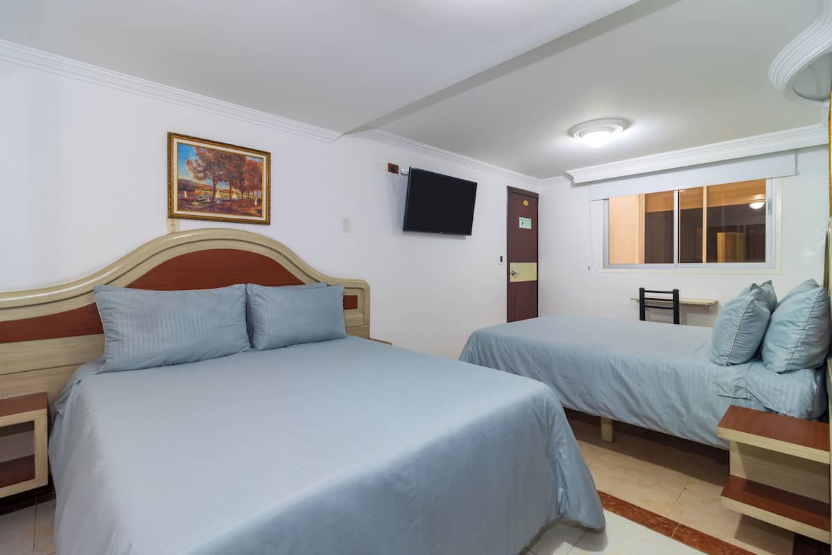 Ein Hotelzimmer mit zwei Betten, einem Fernseher, einem Fenster und einem Bild an der Wand.