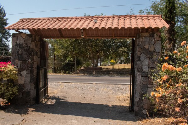 Un arco de piedra con techo de tejas, que da paso a una carretera.