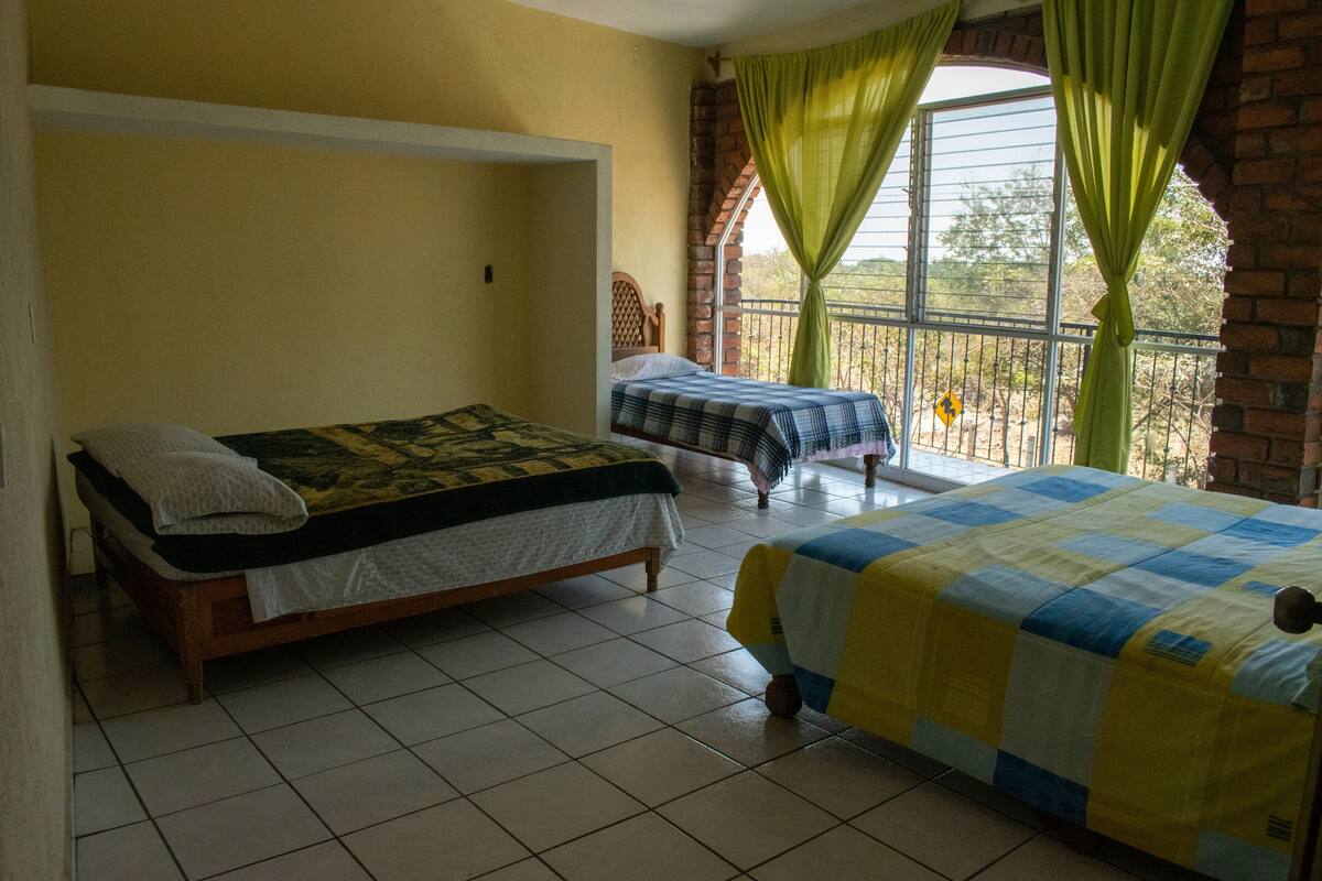 Una habitación con dos camas, una ventana con cortinas y vista al exterior.