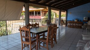 Un patio cubierto con suelo de baldosas, sillas de madera, una mesa y un sofá.