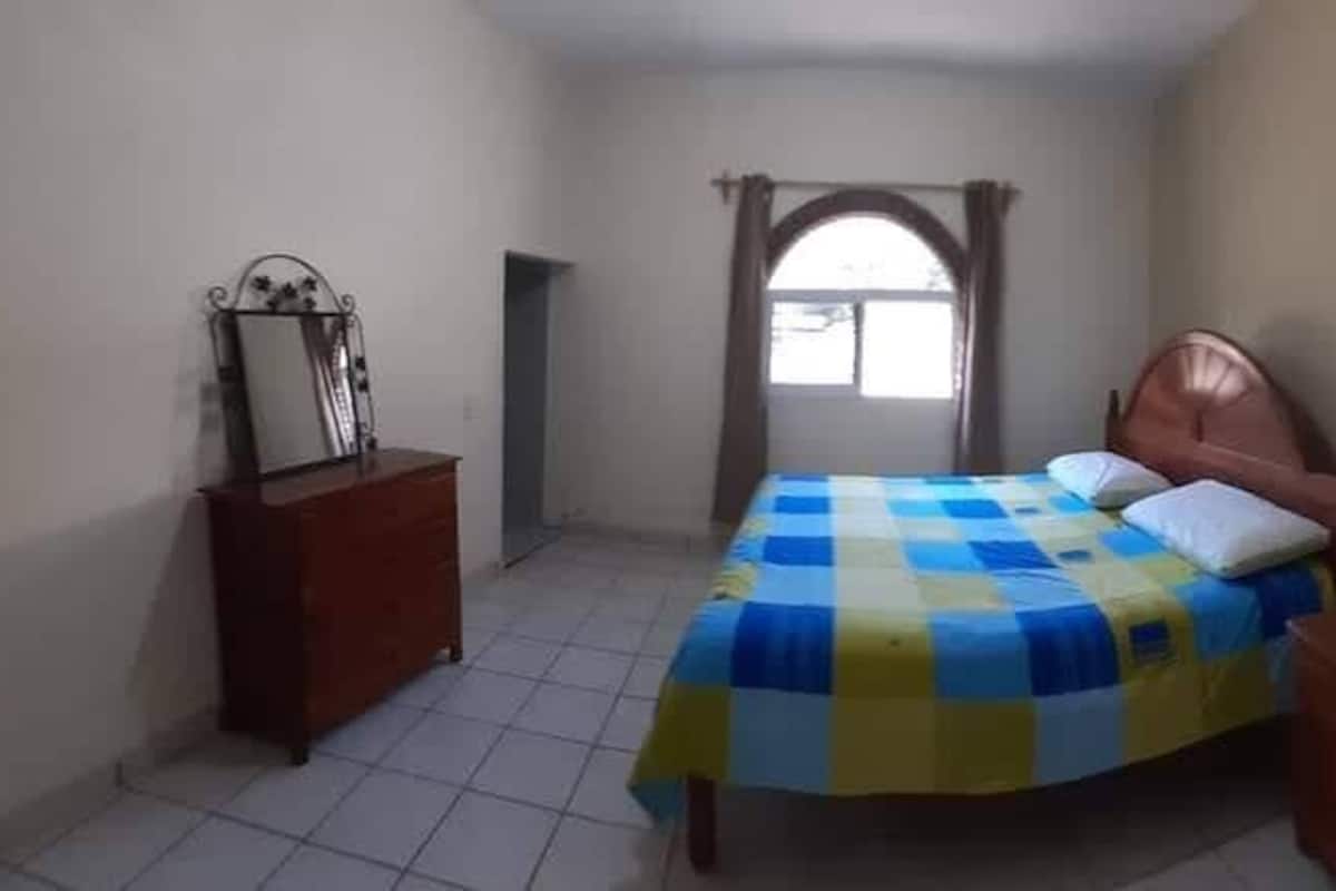 Un dormitorio con cama, cómoda y ventana.