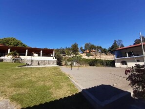 Un barrio residencial con un camino pavimentado, un césped y dos edificios con tejados rojos.