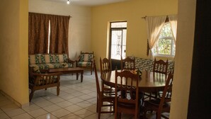 Un comedor con una mesa redonda y sillas, un sofá y un ventanal con cortinas.