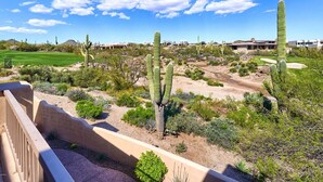 Un paysage désertique avec des cactus, un terrain de golf et un bâtiment doté d’un toit plat.