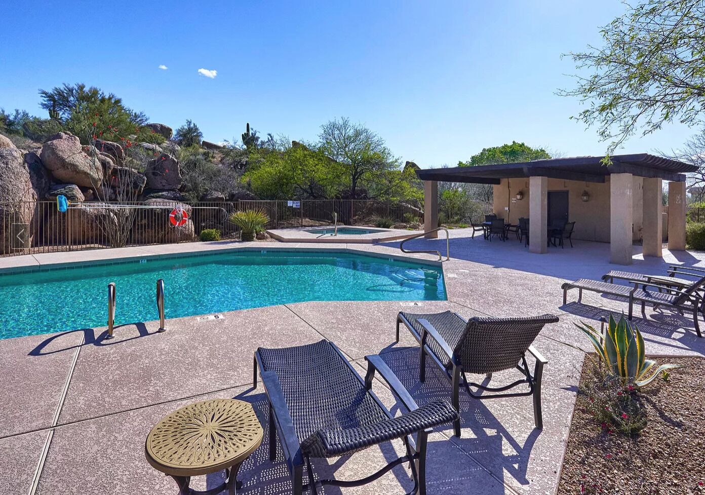 A pool area with lounge chairs and a covered seating area.