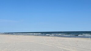 Une plage avec un ciel dégagé et une mer calme.