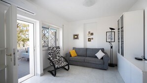 A modern living room with a grey sofa, a patterned armchair, and a floor lamp. - WePuglia - Dimora Capitolo (Monopoli)