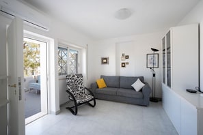 Un salon moderne avec un canapé gris, un fauteuil à motifs et une lampe sur pied.