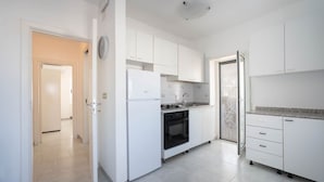 A modern kitchen with white cabinetry, a built-in oven, and a stainless steel refrigerator. - WePuglia - Dimora Capitolo (Monopoli)