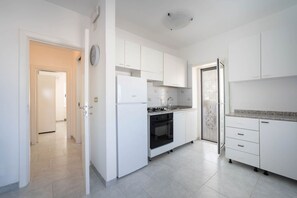 A modern kitchen with white cabinetry, a built-in oven, and a stainless steel refrigerator.