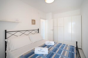 A bedroom with a bed, white walls, a wardrobe, and a door.