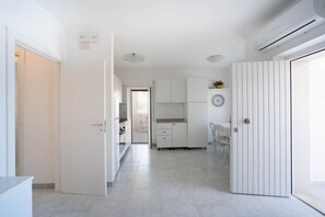 A modern kitchen with white cabinets, a countertop, and a dining area with chairs.
