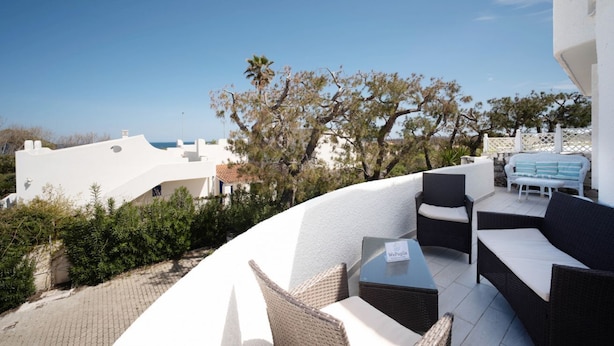 A rooftop terrace with outdoor seating, a view of the sea, and white buildings in the background. - WePuglia - Dimora Capitolo (Monopoli)