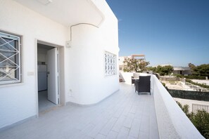 A white building with a balcony, a door, and a window with a lattice design.
