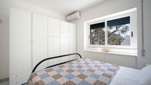 A bedroom with a bed, a window with a view, a wardrobe, and an air conditioning unit. - WePuglia - Dimora Capitolo (Monopoli)
