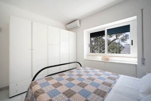 Une chambre avec un lit, une fenêtre donnant sur un beau paysage, une armoire et un appareil de climatisation.