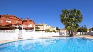 Piscina azzurra e limpida circondata da muri bianchi e palme.