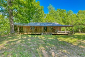 A rustic cabin with a porch, surrounded by lush greenery and trees. - Views of Elk River with wrap-around screened porch for family time (Athens)