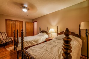 A hotel room with two beds, a wooden chair, a bedside table with a lamp, and a ceiling fan. - Views of Elk River with wrap-around screened porch for family time (Athens)