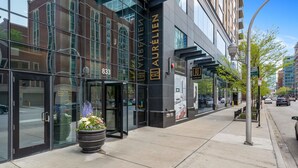 Ein moderner Hotel Eingang mit Glastüren, einem großen Blumentopf und freiem Blick auf die Straße.