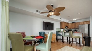 A modern kitchen with a built-in refrigerator, wooden cabinets, and a dining area with green chairs and a table. - Contemporary, clean 1-bedroom mid-town condo with bay view and 1 block to beach. (Ocean City)