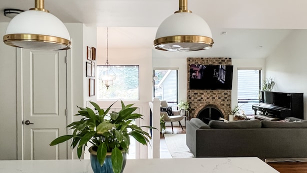 A modern living room with a fireplace, a television, and a piano. There is a dining area with a white table and a blue vase with green plants. - Beautifully renovated hot-tub, large fenced backyard, pet friendly (Kirkland)