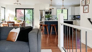 A modern kitchen with white cabinets, a central island, and pendant lighting. - Beautifully renovated hot-tub, large fenced backyard, pet friendly (Kirkland)