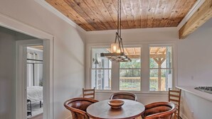 Un coin repas avec une table ronde en bois, six chaises et un luminaire suspendu.