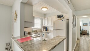 A modern kitchen with white cabinets, a granite countertop, and a built-in oven. - Oceanside Ormond Beach Condo, Steps to Shore! (Ormond Beach)