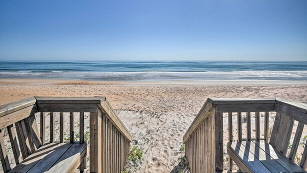 A wooden deck leading to a beach with a clear view of the ocean. - Oceanside Ormond Beach Condo, Steps to Shore! (Ormond Beach)