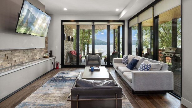 A modern living room with a sofa, coffee table, and a flat-screen TV mounted on the wall. - Monthly 3BR Condo Rental on Whitefish Lake (Whitefish)
