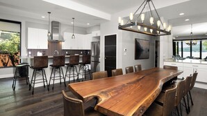 A modern kitchen with a large island, bar stools, and a dining table. - Monthly 3BR Condo Rental on Whitefish Lake (Whitefish)